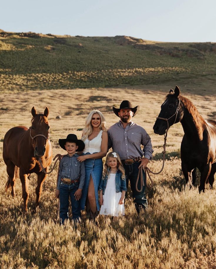 a family poses for a photo with their horses in an open field, surrounded by dry grass