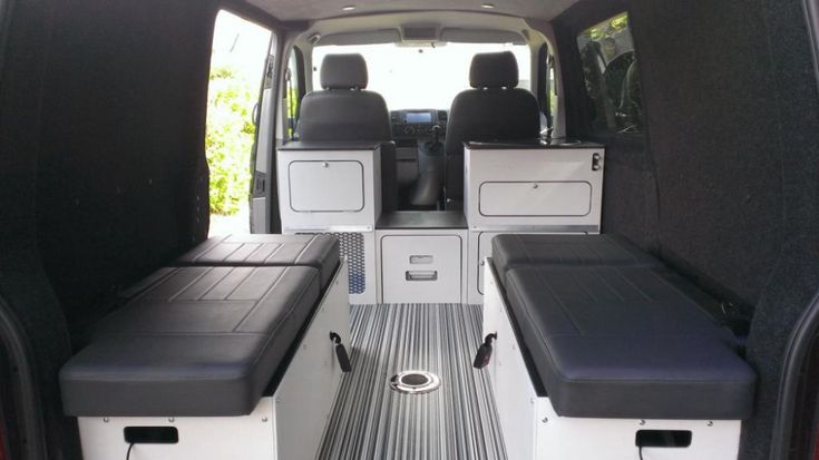 the interior of a white van with black seats and back door open to show storage area