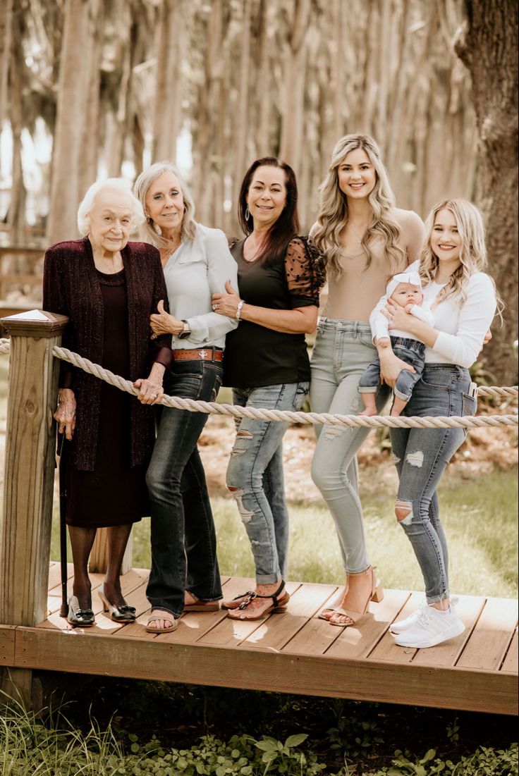 a group of women standing next to each other on a wooden platform in front of trees