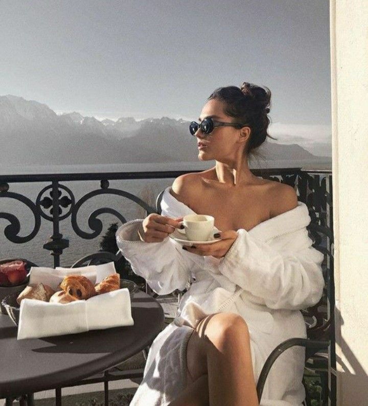 a woman sitting at a table with a cup of coffee and croissants