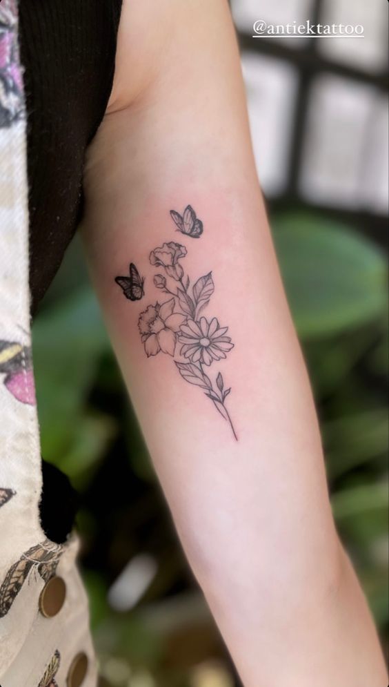 a woman's arm with flowers and butterflies tattoo on the left side of her arm