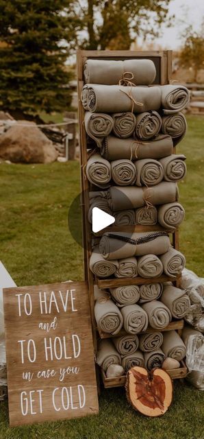 a pile of blankets sitting on top of a grass covered field next to a sign that says, to have and to hold in case you get cold