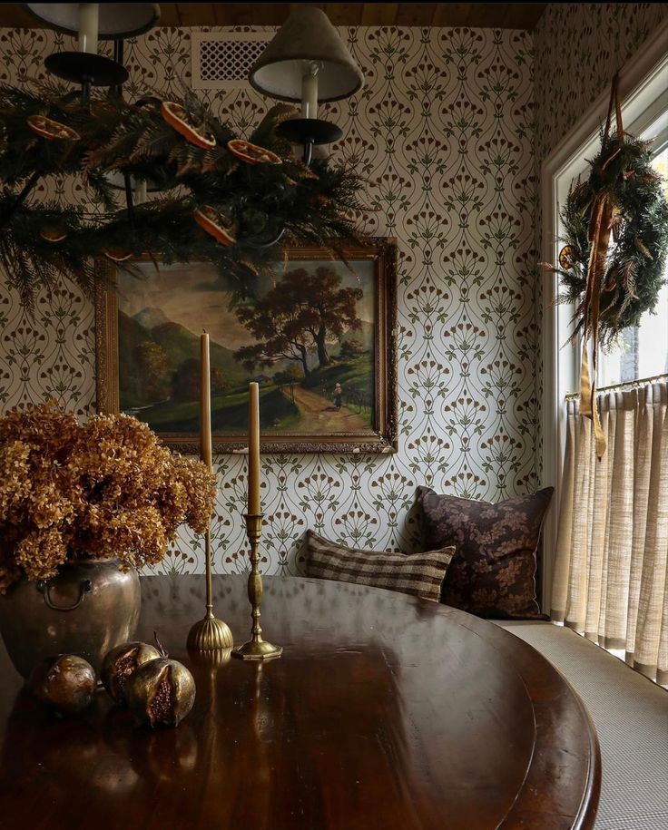 a table with flowers and candles on it in front of a wallpapered room