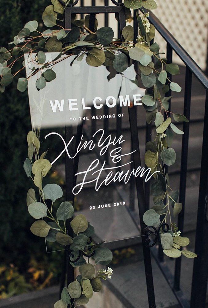 a welcome sign with greenery is hanging from a metal handrail on the stairs