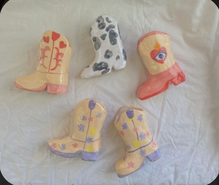 four toy cowboy boots and one cowgirl's boot are on a white sheet