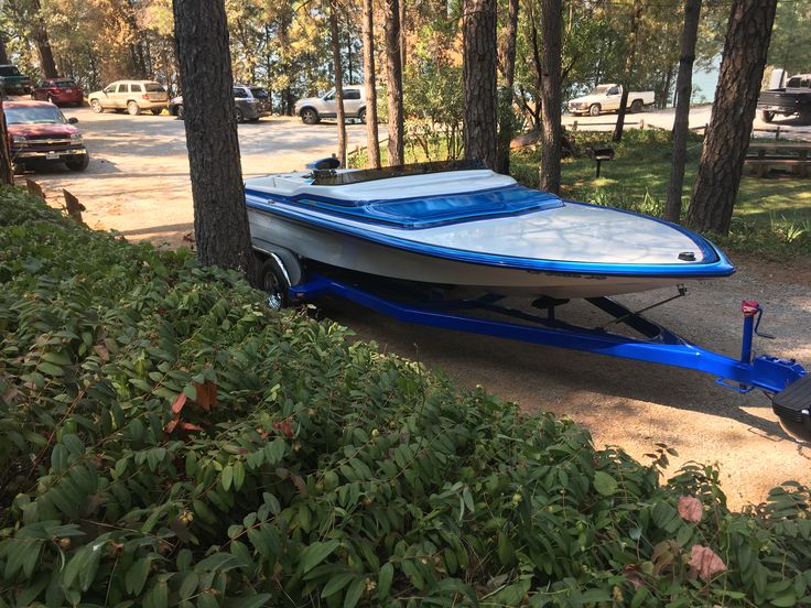 a blue and white boat is parked in the woods