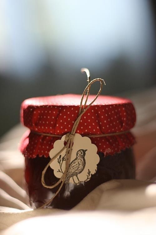 a jar of jam sitting on top of a bed next to a tag with an image of a bird