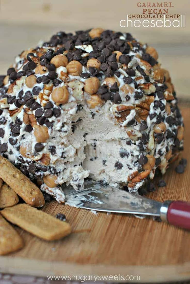 a cake covered in chocolate chips and nuts on a cutting board next to crackers