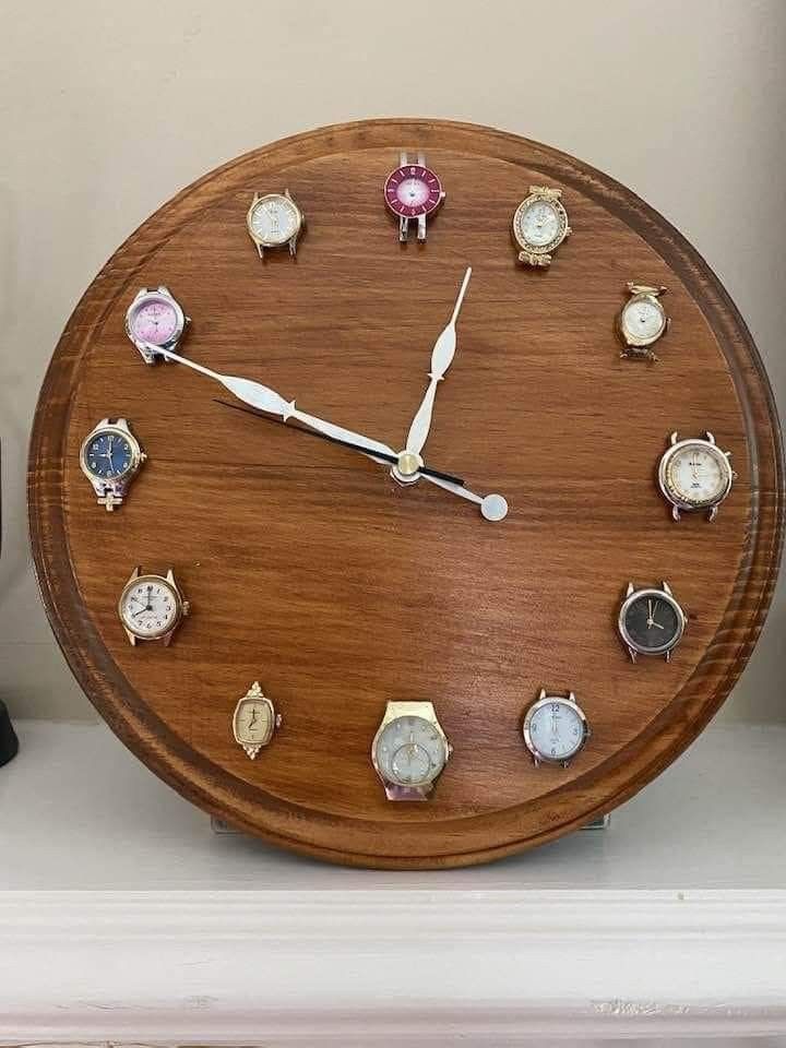 a wooden clock with several different colored watches on it's face and hands, sitting on a shelf