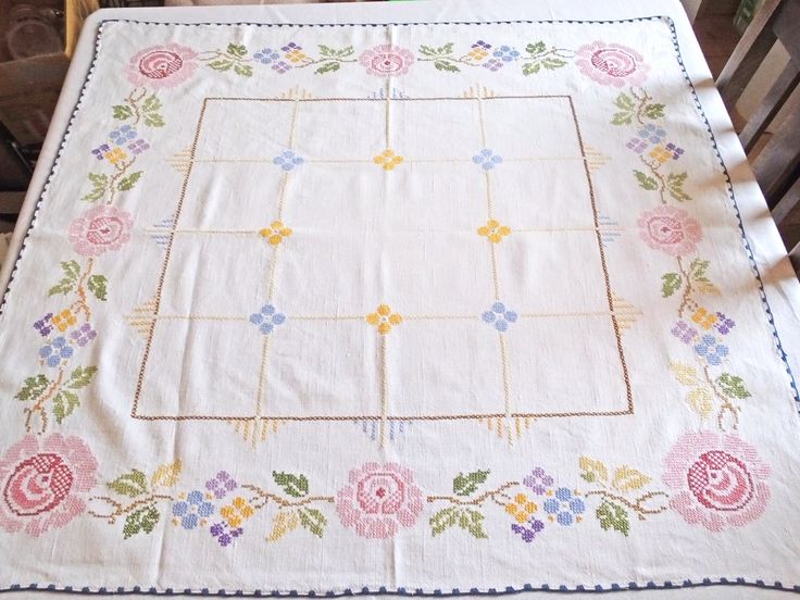 an embroidered tablecloth with flowers on it