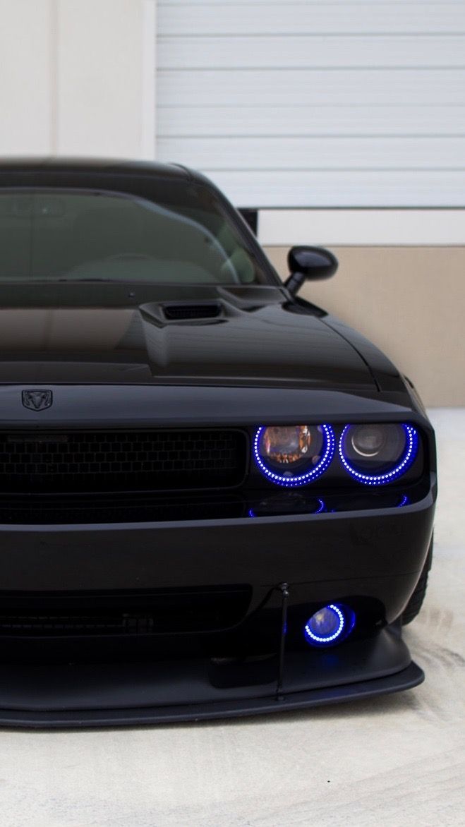 the front end of a black sports car with blue lights