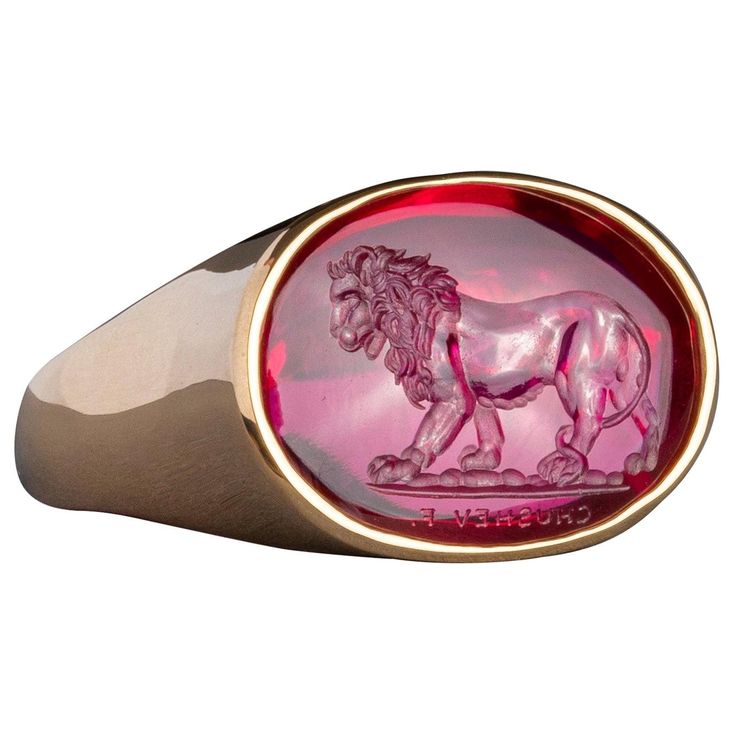 This exquisite intaglio is masterfully engraved onto man made corundum and features a lion. The intaglio is set in an 18K gold signet ring. Production time for this piece is 12-14 weeks. Can be made in any size ranging from 8-12. Chavdar Chushev is an artist, restorer, jeweler, and master of the ancient art of gem carving. His extensive knowledge of gemstones and precious metals is complimented by a familiarity with more unusual materials, such as exotic woods, organic gems, and fossils. This un Luxury Engraved Ruby Ring, Luxury Carved Yellow Gold Signet Ring, Luxury Formal Signet Ring With Intaglio, Luxury Carved Oval Signet Ring, Luxury 14k Gold Signet Ring With Intaglio, Luxury Oval Signet Ring With Intaglio, Luxury Round Signet Ring With Intaglio, Luxury Engraved Oval Ruby Ring, Elegant Red Intaglio Signet Ring