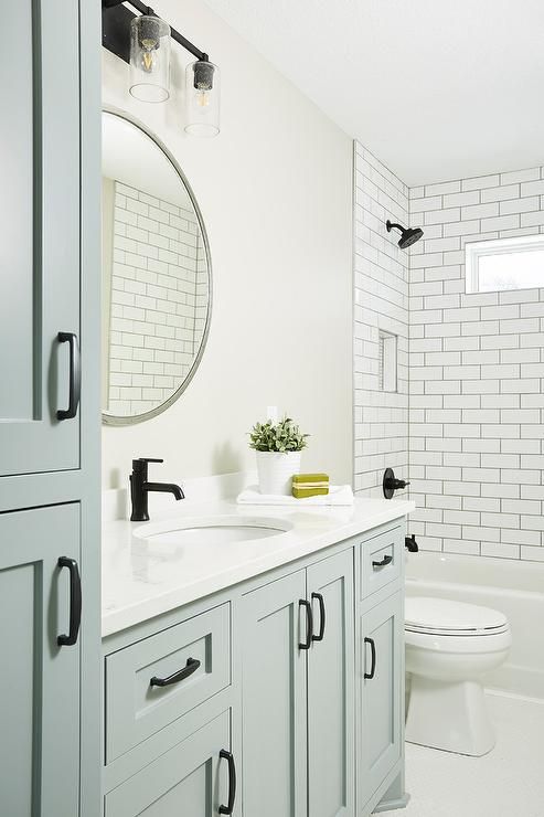 a white bathroom with black handles on the cabinet doors and a mirror over the sink