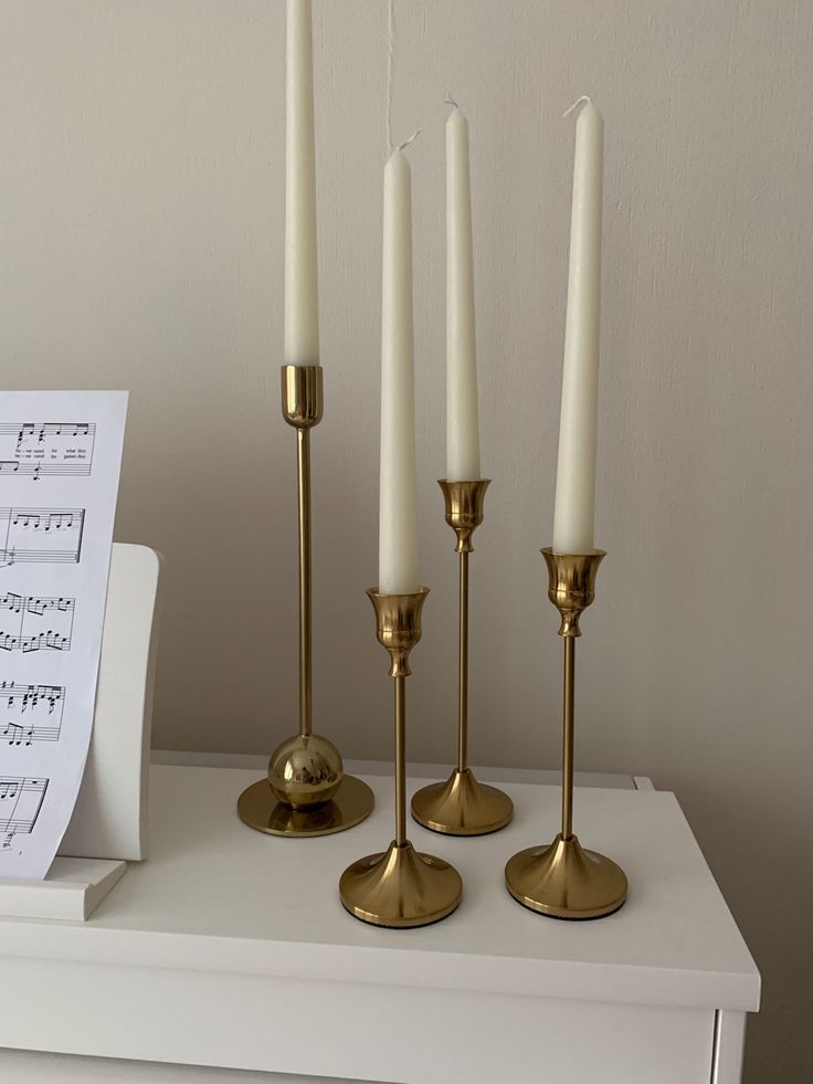 four candles are sitting on a table with sheet music