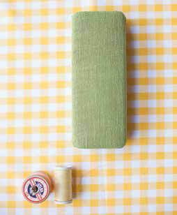 a yellow and white checkered table cloth next to two spools of thread