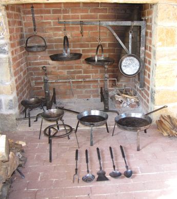 pots and pans are hanging on the wall in front of an open fire place