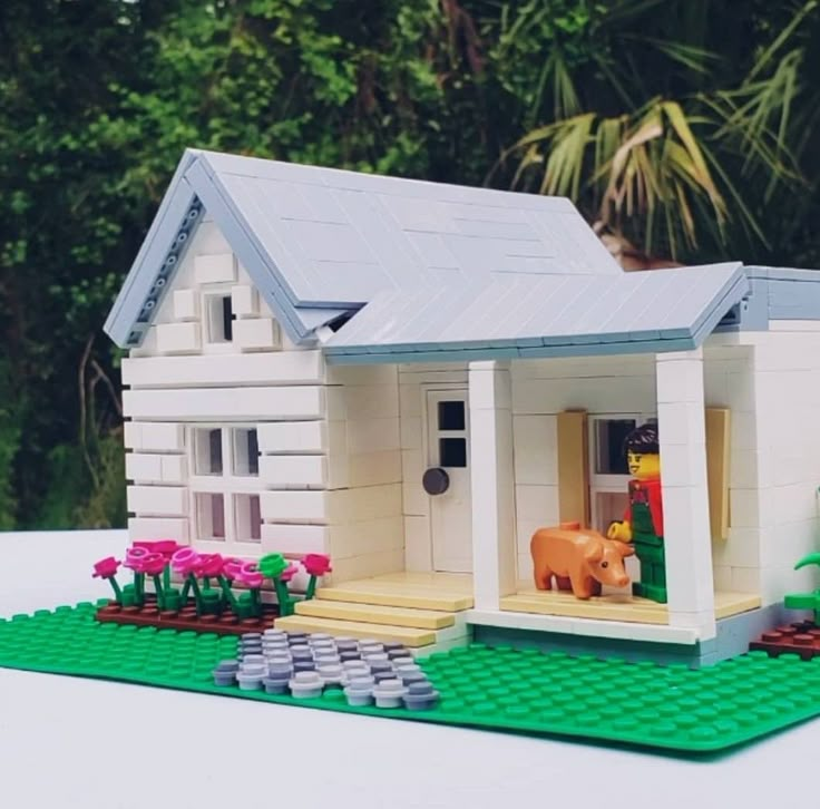 a toy house made out of legos sitting on top of a table with flowers