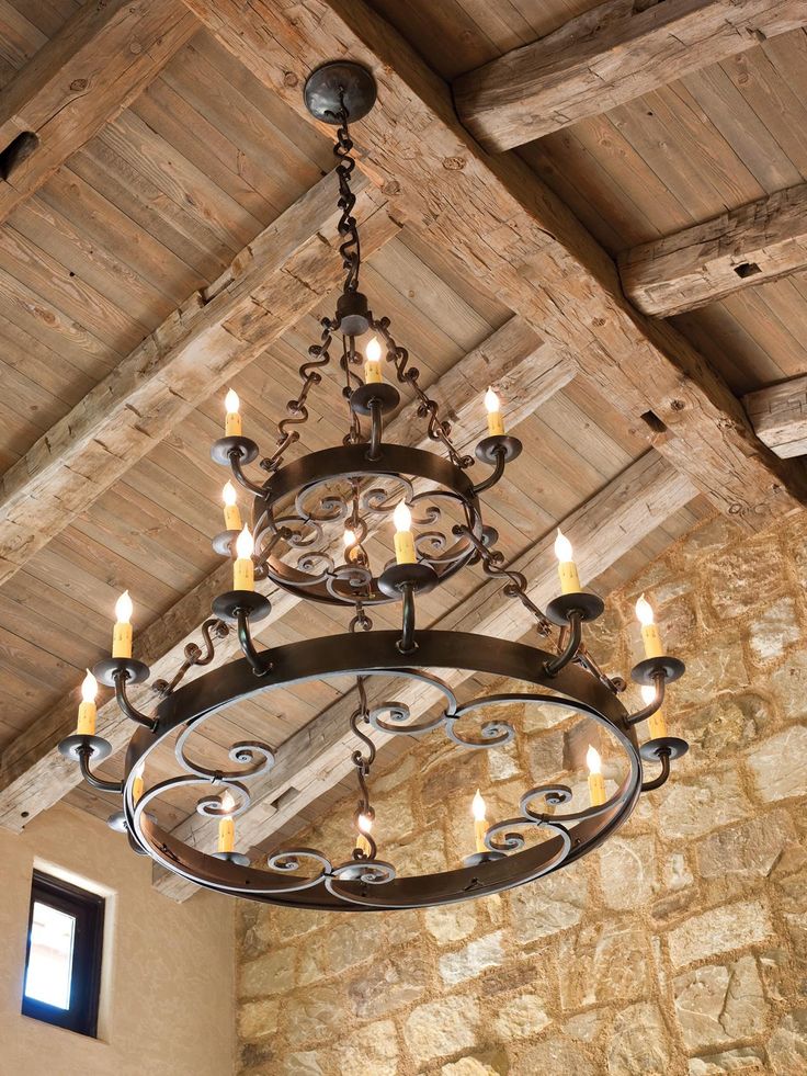 a chandelier hanging from the ceiling in a room with stone walls and wood beams