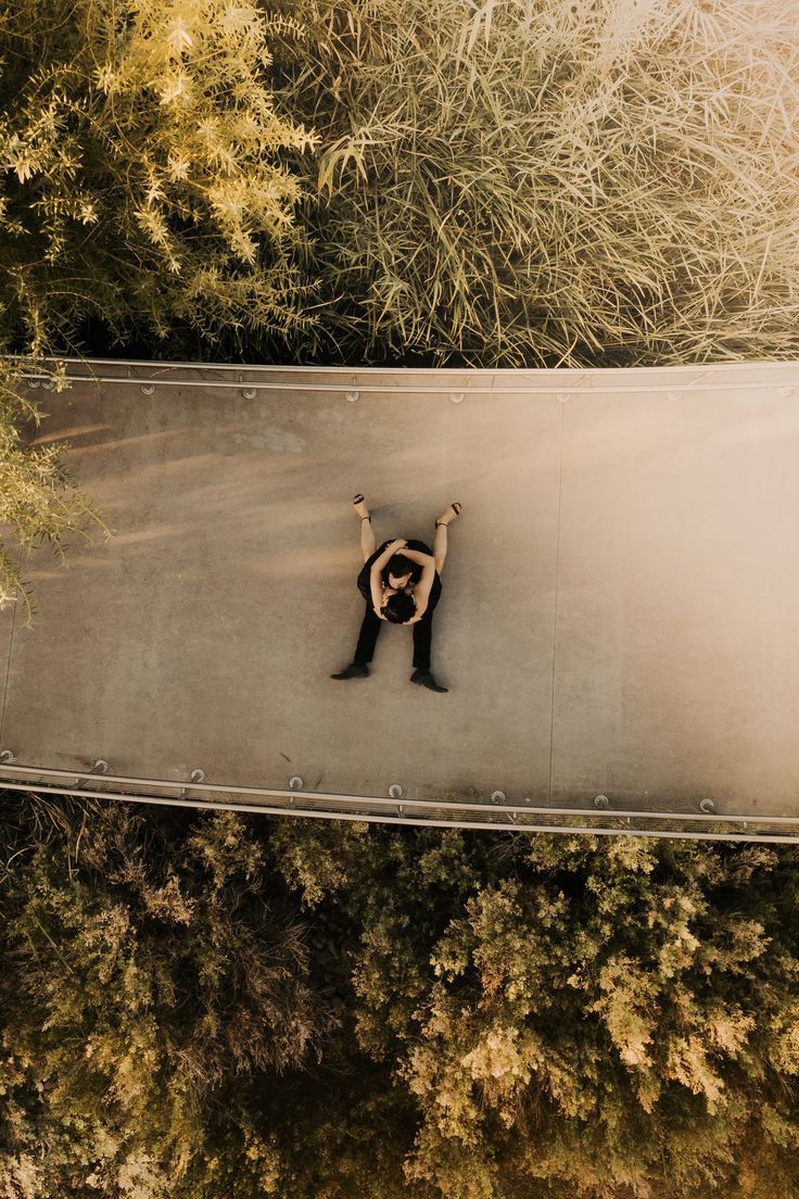 an aerial view of a person standing in the middle of a forest with their arms up