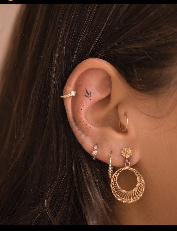 a woman wearing gold ear piercings with an open circle design on her left ear