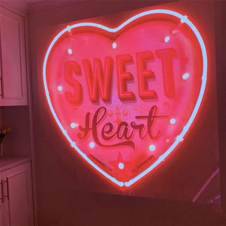 a heart shaped neon sign with the words sweet heart on it's side in a kitchen