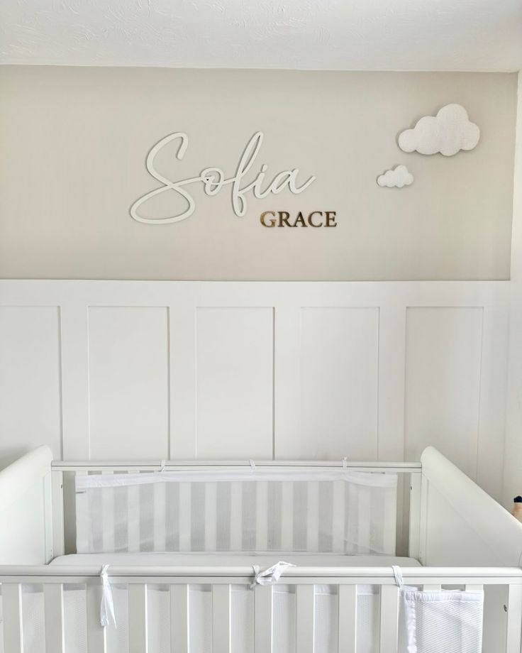 a white crib with the name soffaa grace above it and clouds on the wall