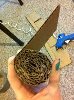 a person is holding a piece of cardboard with scissors on top of it and some yarn in front of them