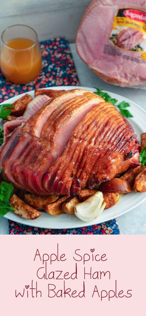 an apple spice glazed ham with baked apples is on a plate next to a glass of orange juice