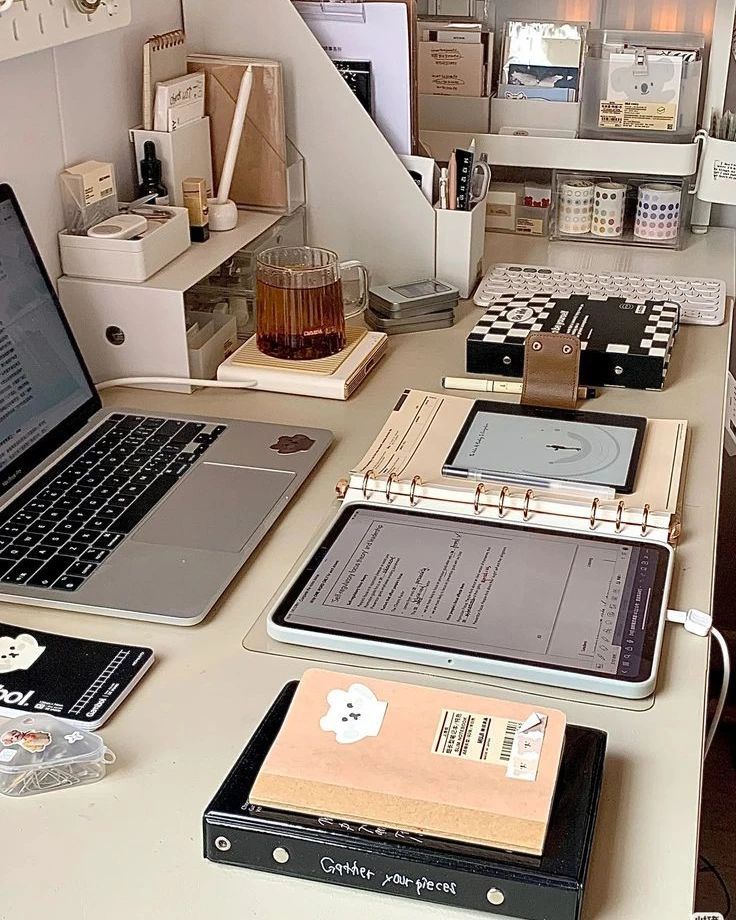 an office desk with several laptops and books on it