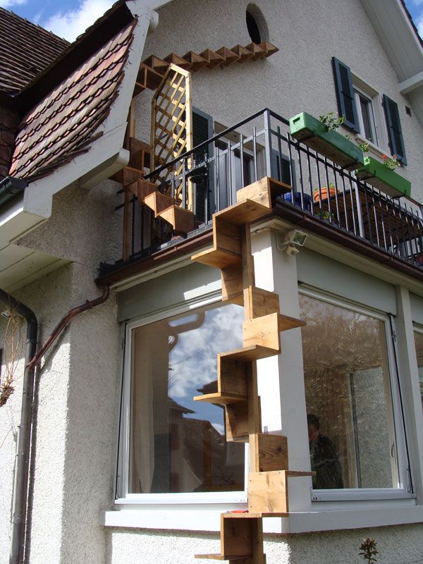 a house that has some stairs going up the side of it and there is a balcony on top