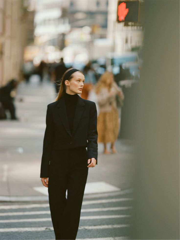 a woman is walking down the street wearing a black suit