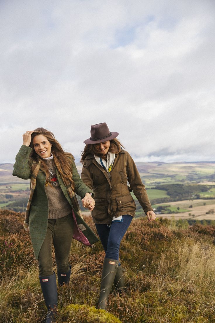 two people walking on a grassy hill with one holding the hand of another person's hand