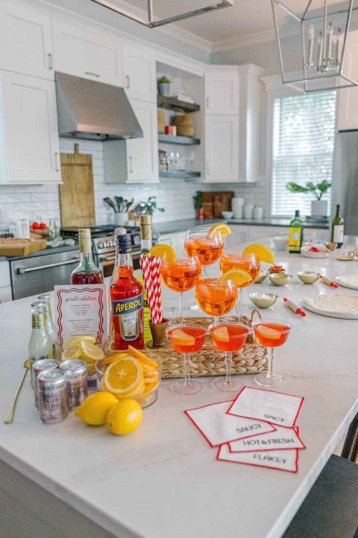 the kitchen counter is covered with glasses and bottles of wine, lemons, and gin