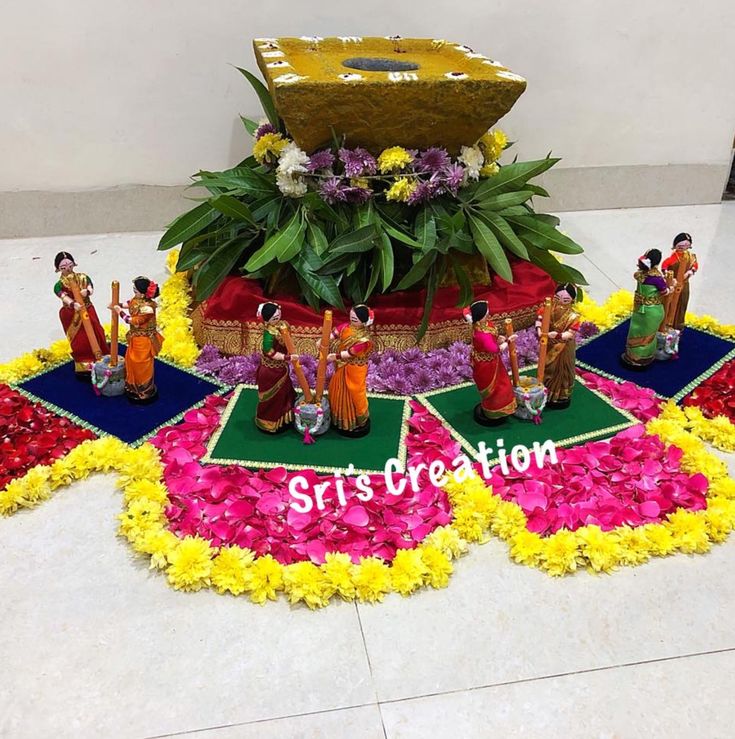 an arrangement of flowers, figurines and decorations on the floor for a celebration