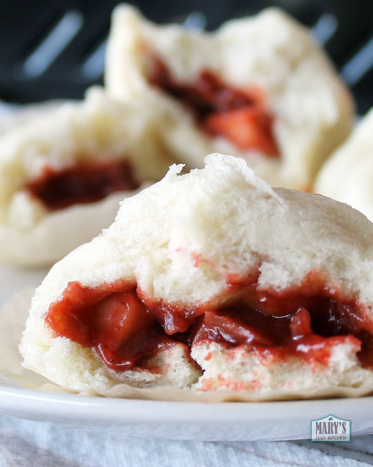 strawberry shortcakes with powdered sugar and jelly filling on a white plate, ready to be eaten