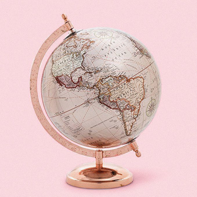 an old world globe on a stand against a pink background