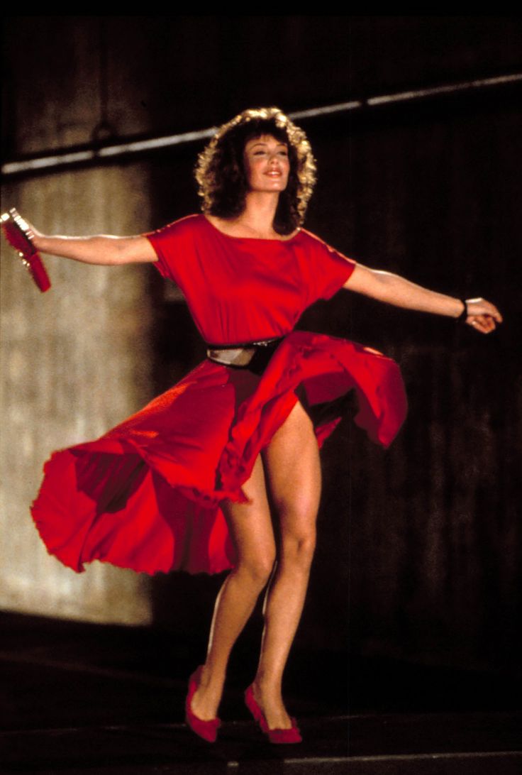 a woman in a red dress is dancing with her legs spread out and arms outstretched