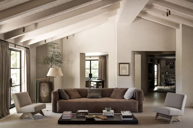 a living room with couches, chairs and tables inside of the house that is decorated in neutral colors