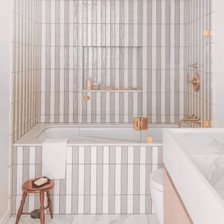 a bathroom with white and beige tiles on the walls, floor, and bathtub