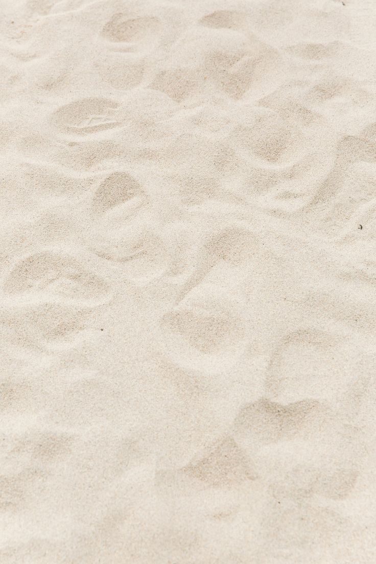 an orange frisbee laying on top of a white sandy beach next to the ocean