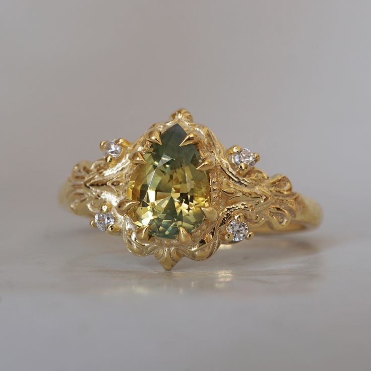 a fancy yellow gold ring with an oval cut green sapphire surrounded by small white diamonds