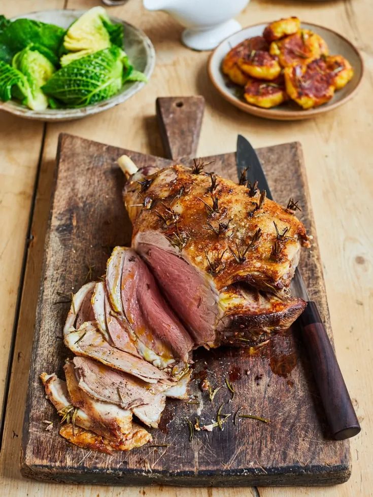 sliced ham on cutting board with knife and other food items