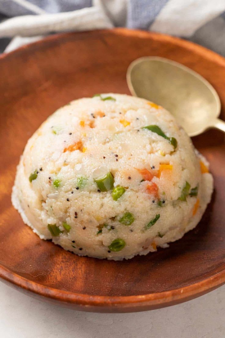 a wooden plate topped with rice on top of a table next to a metal spoon