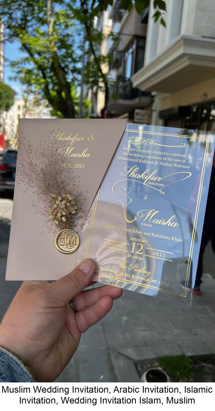 a person holding up a wedding card in front of a building on a street corner