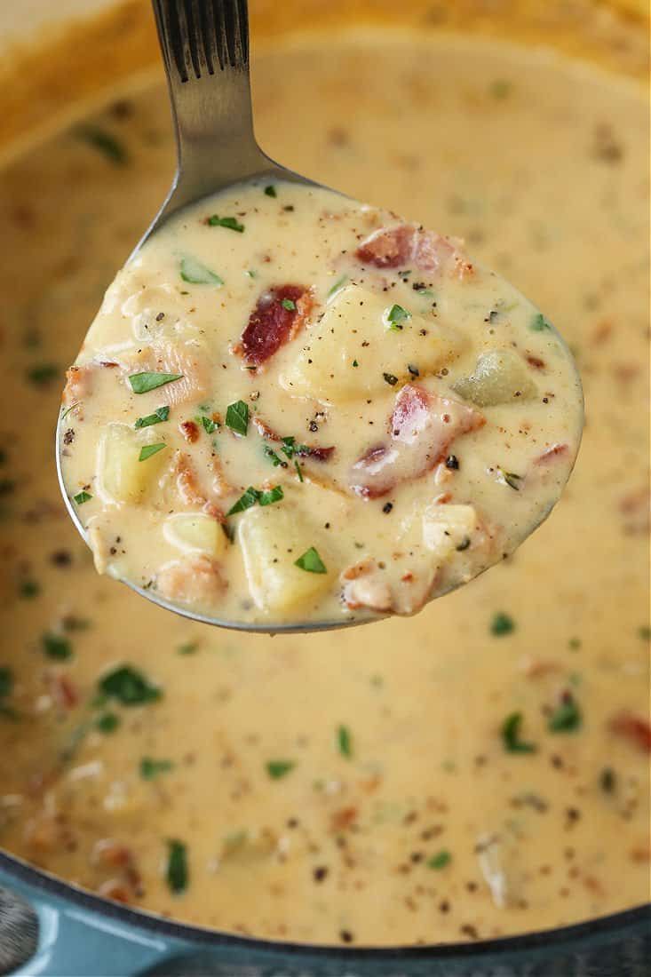 a ladle full of soup with meat and cheese in it, being held by a spoon