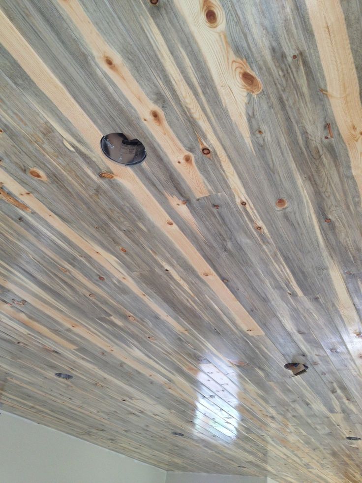 the ceiling is covered with wood planks and has holes in it for light to see