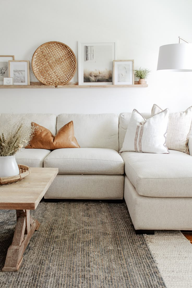 a living room with white couches and pictures on the wall above it's coffee table