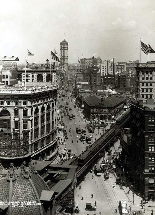 an old black and white photo of a busy city street with tall buildings in the background