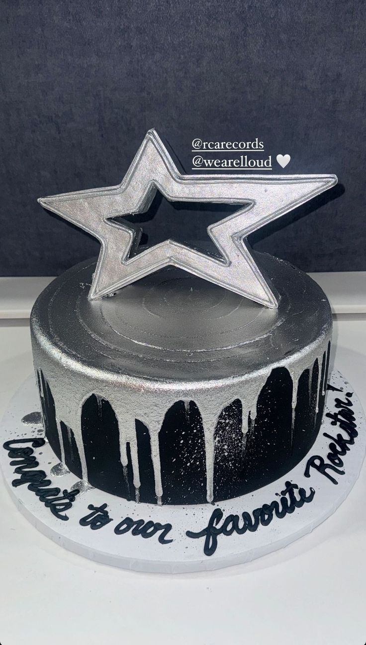 a black and white cake with silver icing on it's side, topped with a star