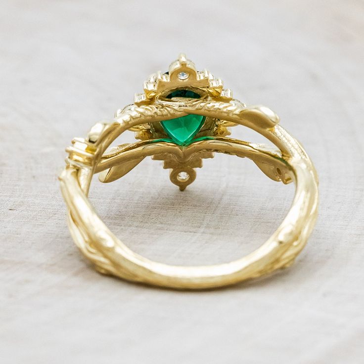 a gold ring with a green stone in the center